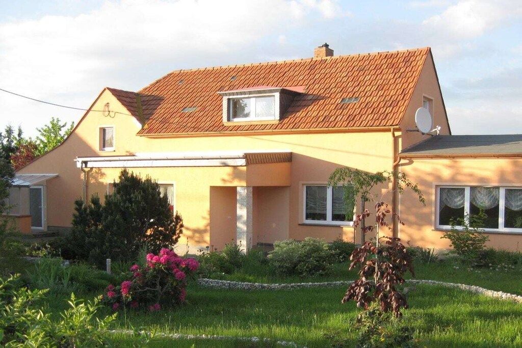 Een twee verdiepingen tellend huis met een schuin dak, een schotelantenne en een klein raam.