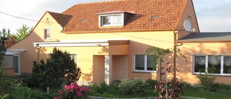 A two-story house with a sloped roof, a satellite dish, and a small window.