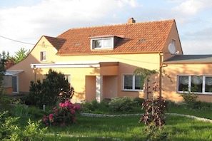 Ein zweistöckiges Haus mit Satteldach, einer Satellitenschüssel und einem kleinen Fenster.