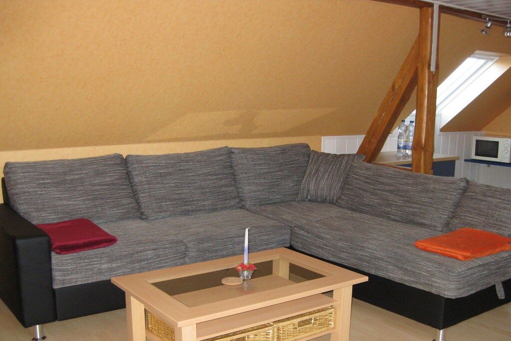 En grå modulsofa med et sofabord i glas i et rum med skrå vægge.