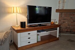 Een flatscreen televisie op een houten dressoir met een lamp, boeken en decoratieve objecten.