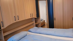 Un dormitori amb llit, armari de fusta i una petita taula de nit.