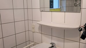 Un bany amb un rentapans blanc, un mirall i un vàter.