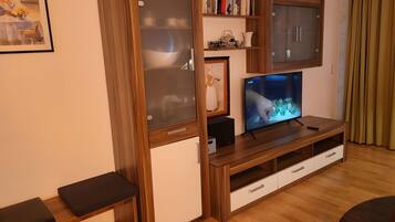 Ein Wohnzimmer mit einer Holzunterhaltungsecke, einem Flachbildfernseher und einer Bank.