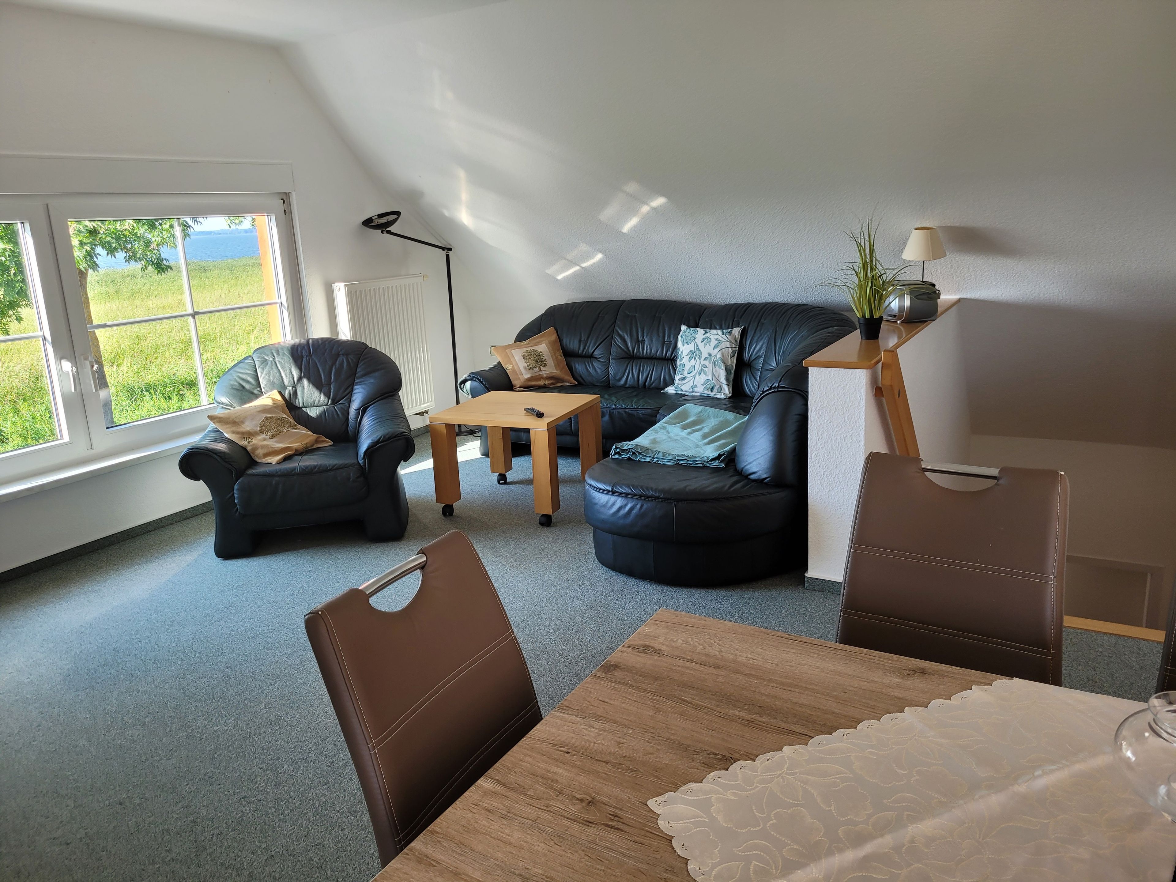 Een moderne woonkamer met een leren bank, een houten salontafel en een eettafel met stoelen.