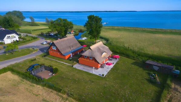 A rural property with a large house, a smaller building with a thatched roof, and a boat docked by the water.