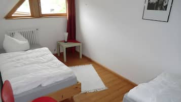 Makuuhuoneessa on kerrossänky, pieni pöytä, patteri ja ikkuna, jossa on verhot.