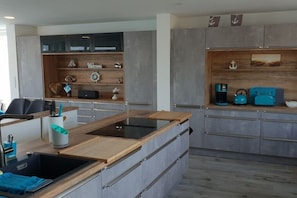 A modern kitchen with a built-in stove, wooden shelves, and a coffee machine. - Holiday home with 3 bedrooms (Bitterfeld)