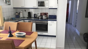 A compact kitchen with white cabinets, a microwave, an oven, and a coffee maker. - Apartment 'Zinnowitz, Dünenstraße WE 3' with private terrace and Wi-Fi (Zinnowitz)