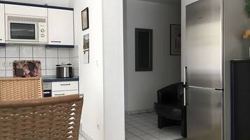 Una cocina moderna con armarios blancos, microondas, tostadora y refrigerador.