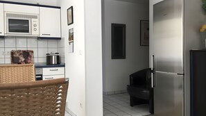 A modern kitchen with white cabinets, a microwave, a toaster, and a refrigerator. - Apartment 'Zinnowitz, Dünenstraße WE 3' with private terrace and Wi-Fi (Zinnowitz)