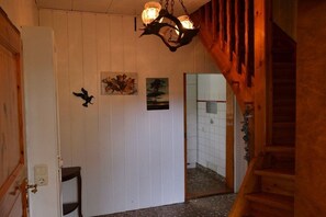 A wooden interior with a staircase, a white door, and a hallway leading to a tiled room. - Rhododendron Colorful Door (Prerow)
