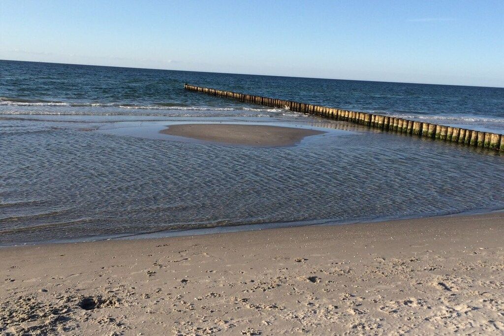 Une plage avec une jetée en bois qui s’avance dans l’eau.