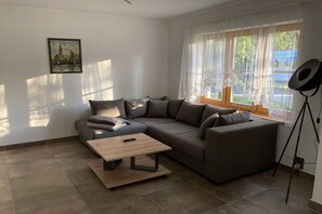 A modern living room with a sectional sofa, a coffee table, and a tripod on the floor. - ||-----------------------Rhododendron EG----------------|| (Prerow)