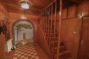 Ein Holzinnenraum mit einer Treppe, einem Heizkörper und einem Schachbrettfußboden.