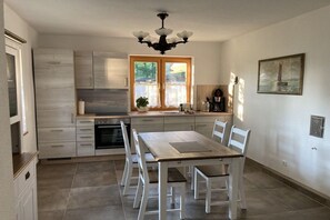 A modern kitchen with a dining table, chairs, a chandelier, and a window with curtains. - ||-----------------------Rhododendron EG----------------|| (Prerow)