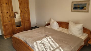 A bedroom with a wooden bed, a large mirror, and a painting on the wall.