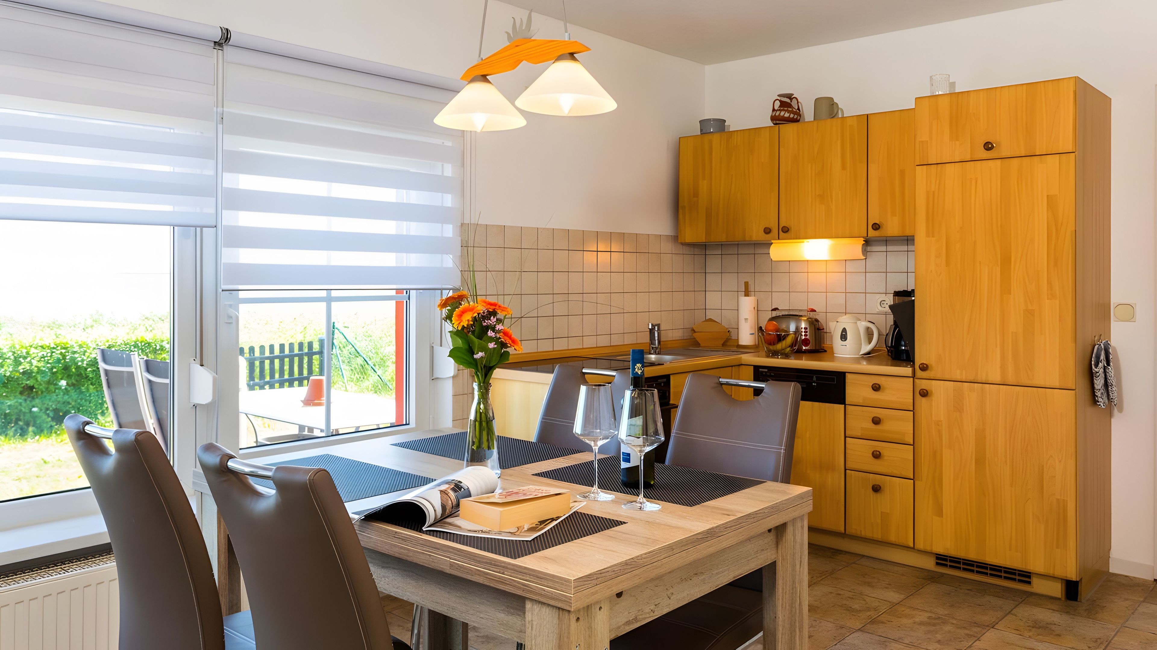 Una cocina moderna con armarios de madera, una mesa de comedor con sillas y vistas al exterior.