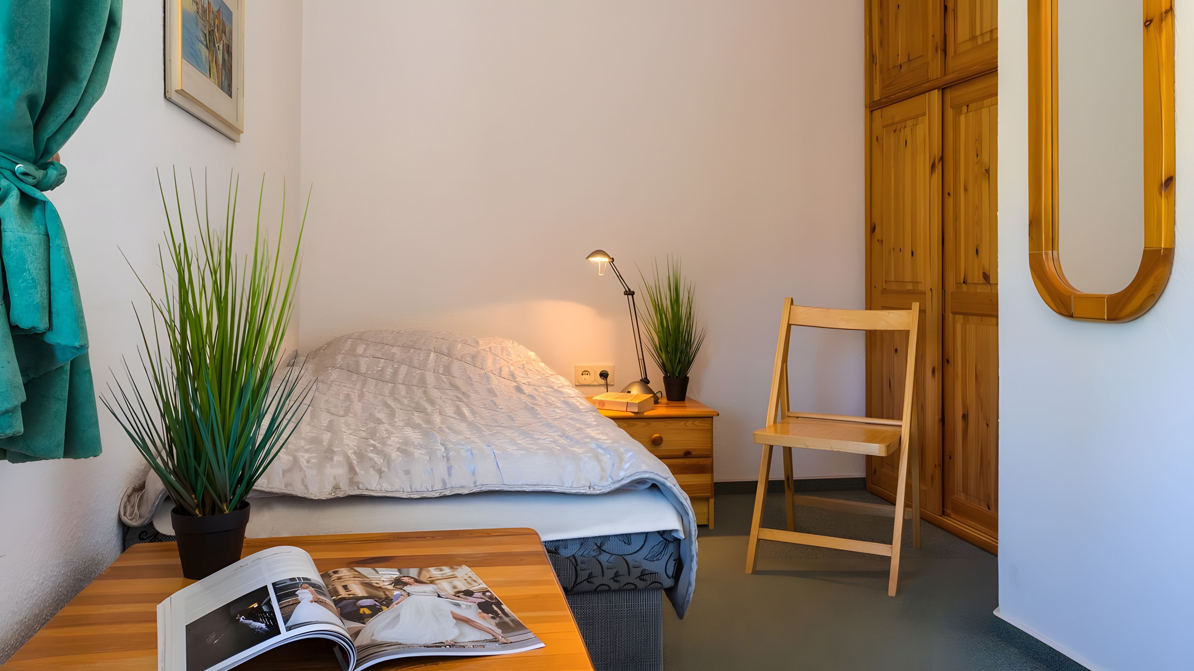 Une chambre à coucher avec un lit, une table de chevet, une lampe, une chaise et un magazine sur la table.