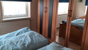 Un dormitori amb llit, armari i finestra.