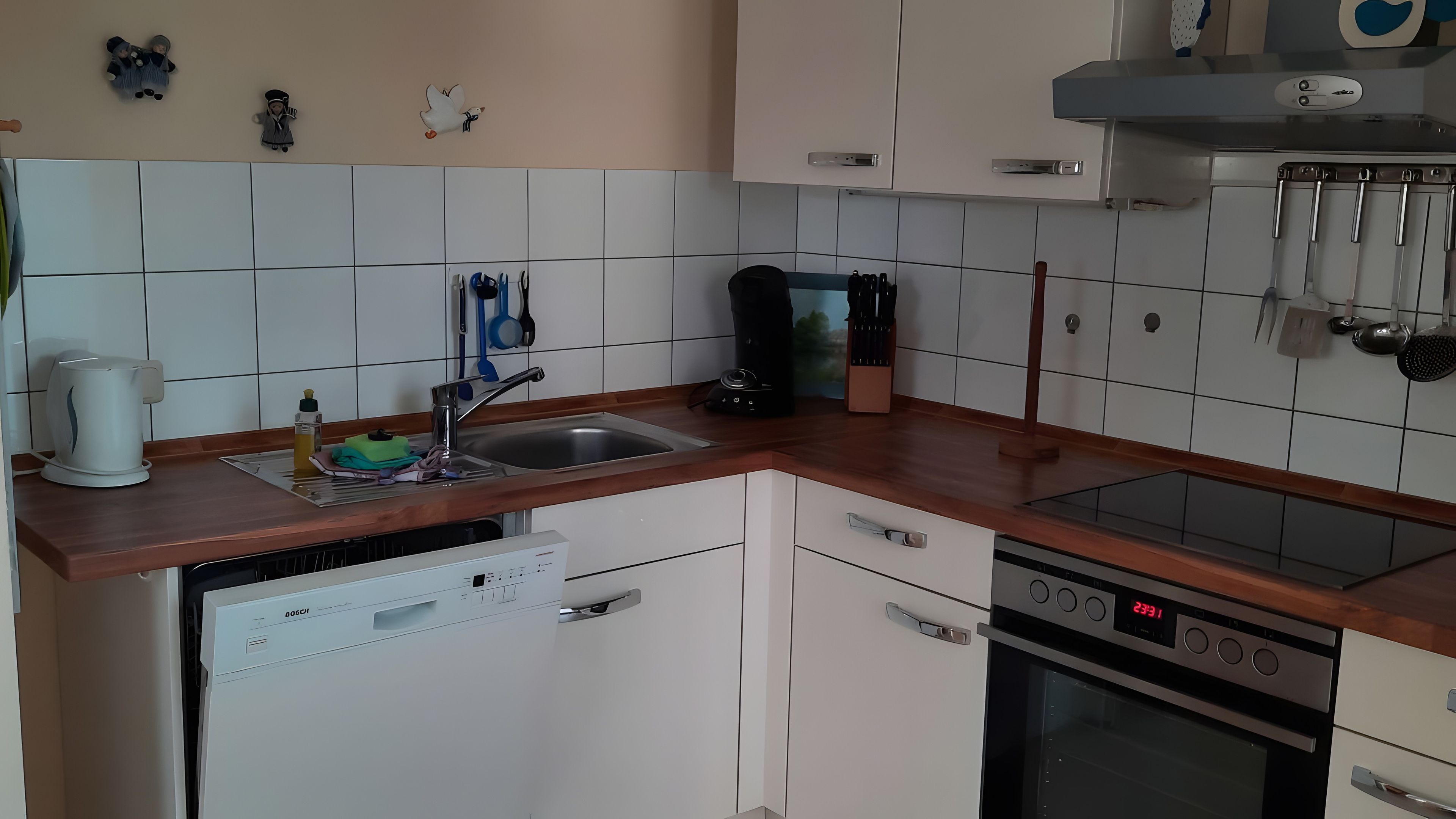 Eine Küche mit weißen Schränken, einer Edelstahlspüle, einer Kaffeemaschine und einem Geschirrspüler.