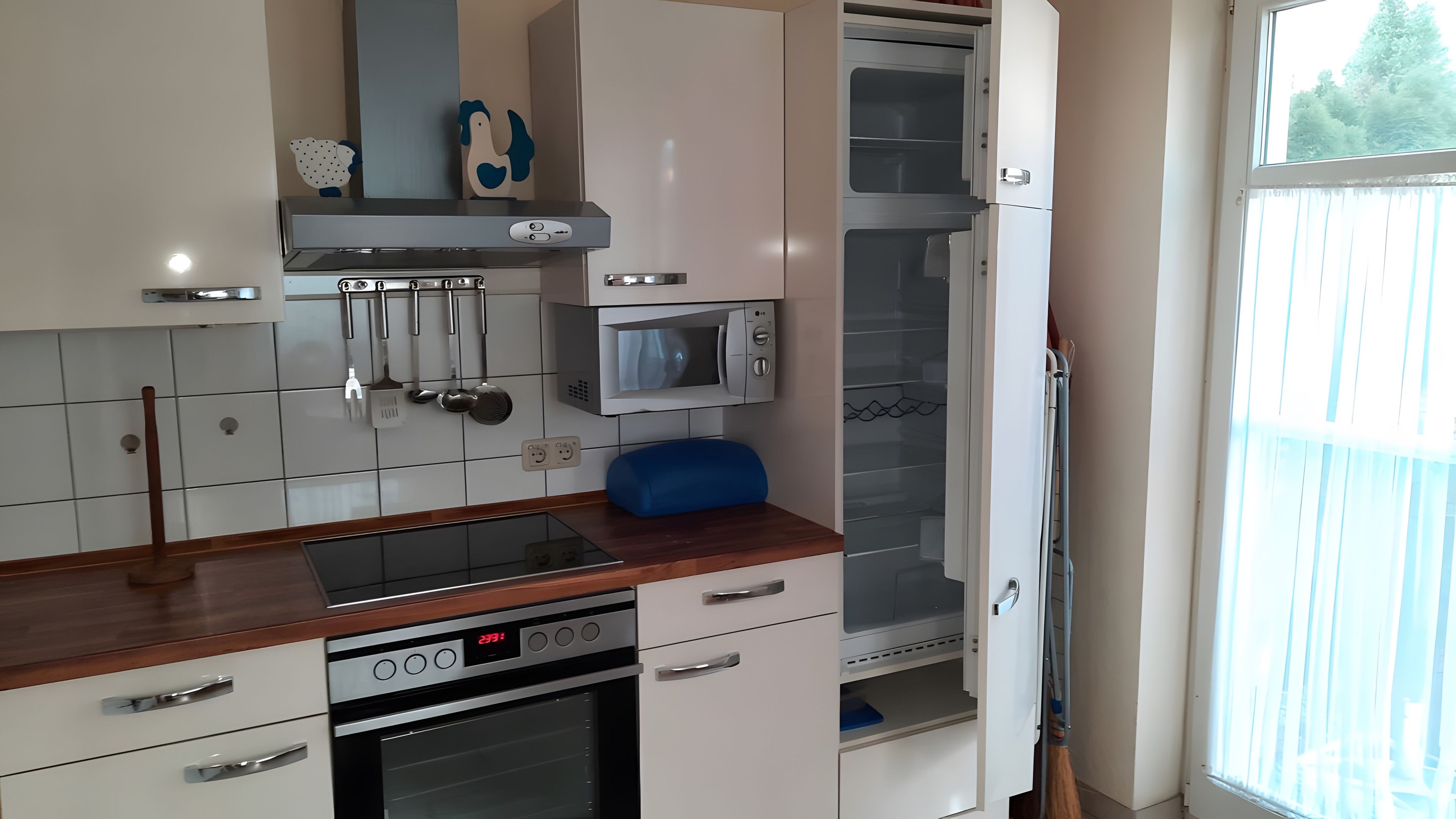Eine Küche mit Backofen, Mikrowelle und verschiedenen Küchenutensilien, die an der Wand hängen.