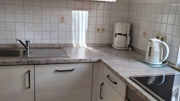 Eine Küche mit Spüle, Arbeitsplatte, Schränken, einer Kaffeemaschine und einem Wasserkocher.