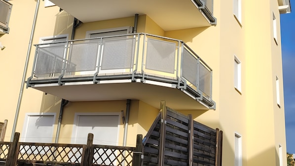 Ein mehrstöckiges Gebäude mit einem Balkon, der Metallgeländer und eine niedrige Holzzahlung aufweist.