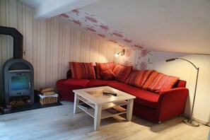 Uma sala de estar acolhedora com um sofá vermelho, uma mesa de centro de madeira, uma lareira e um abajur.