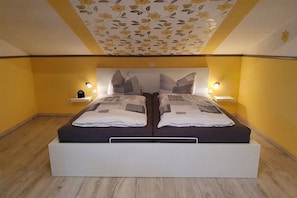 Ein Doppelbett mit Kopfteil, Nachttischen und einer Decke mit floralem Muster.