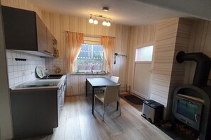 Eine kleine Küche mit Esstisch, Einbauherd und einem Fenster mit Vorhängen.