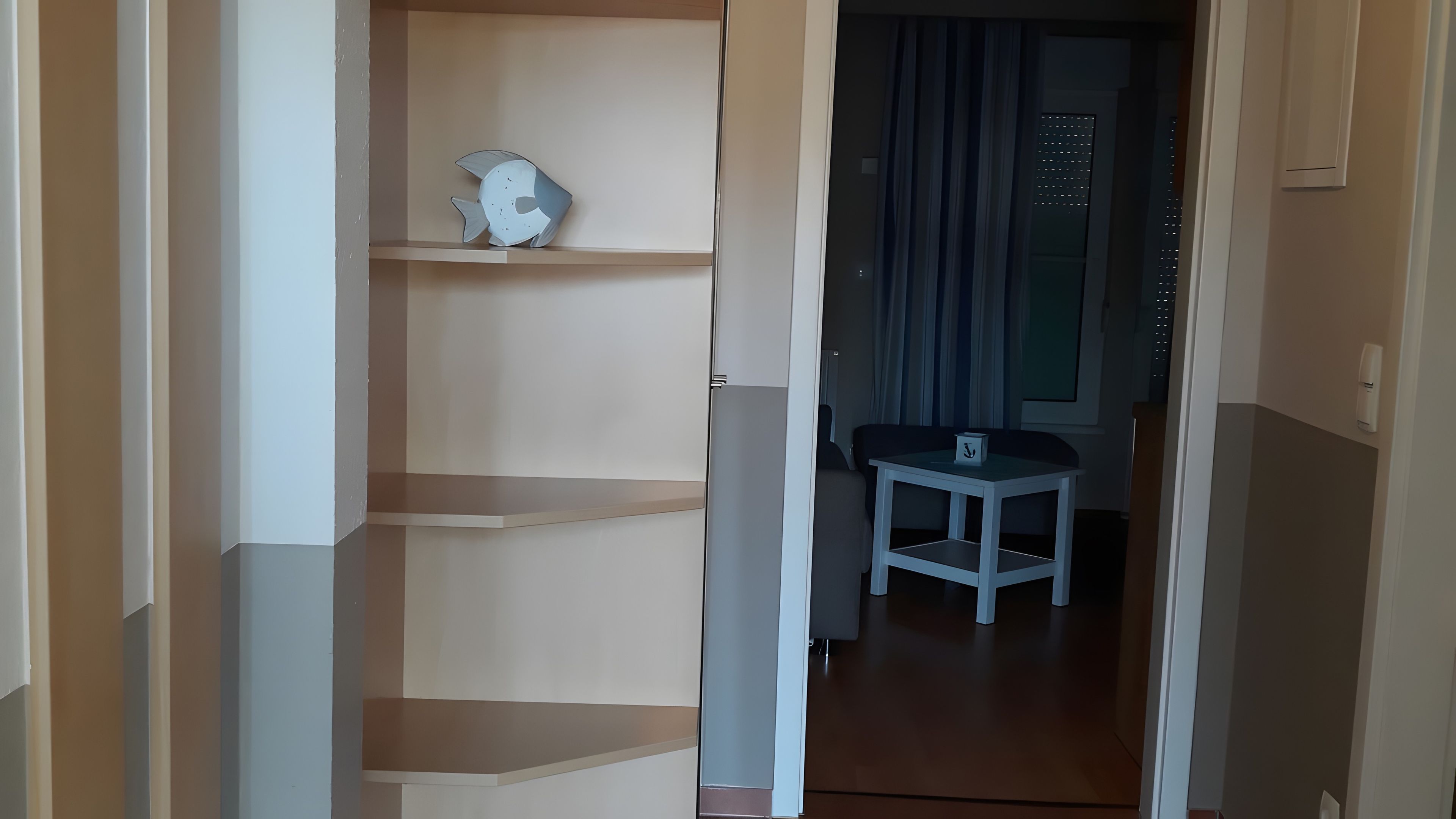 Ein Flur mit einer Treppe, die zu einem Zimmer mit Fenster und kleinem Tisch führt.