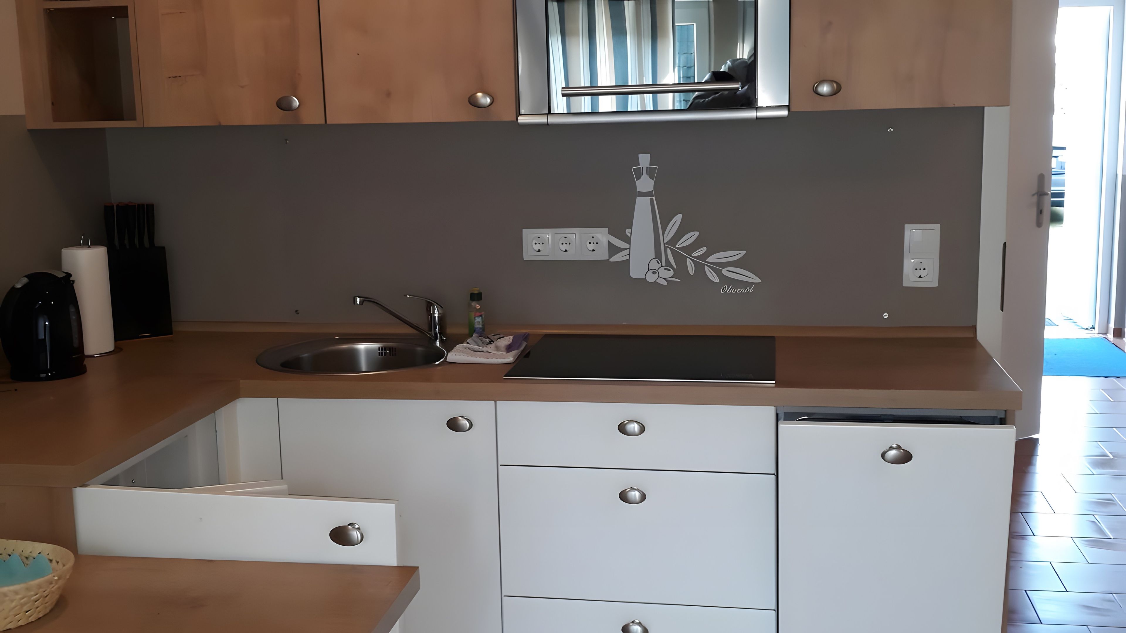 Una cocina moderna con pileta de acero inoxidable, armarios de madera y lavavajillas integrado.
