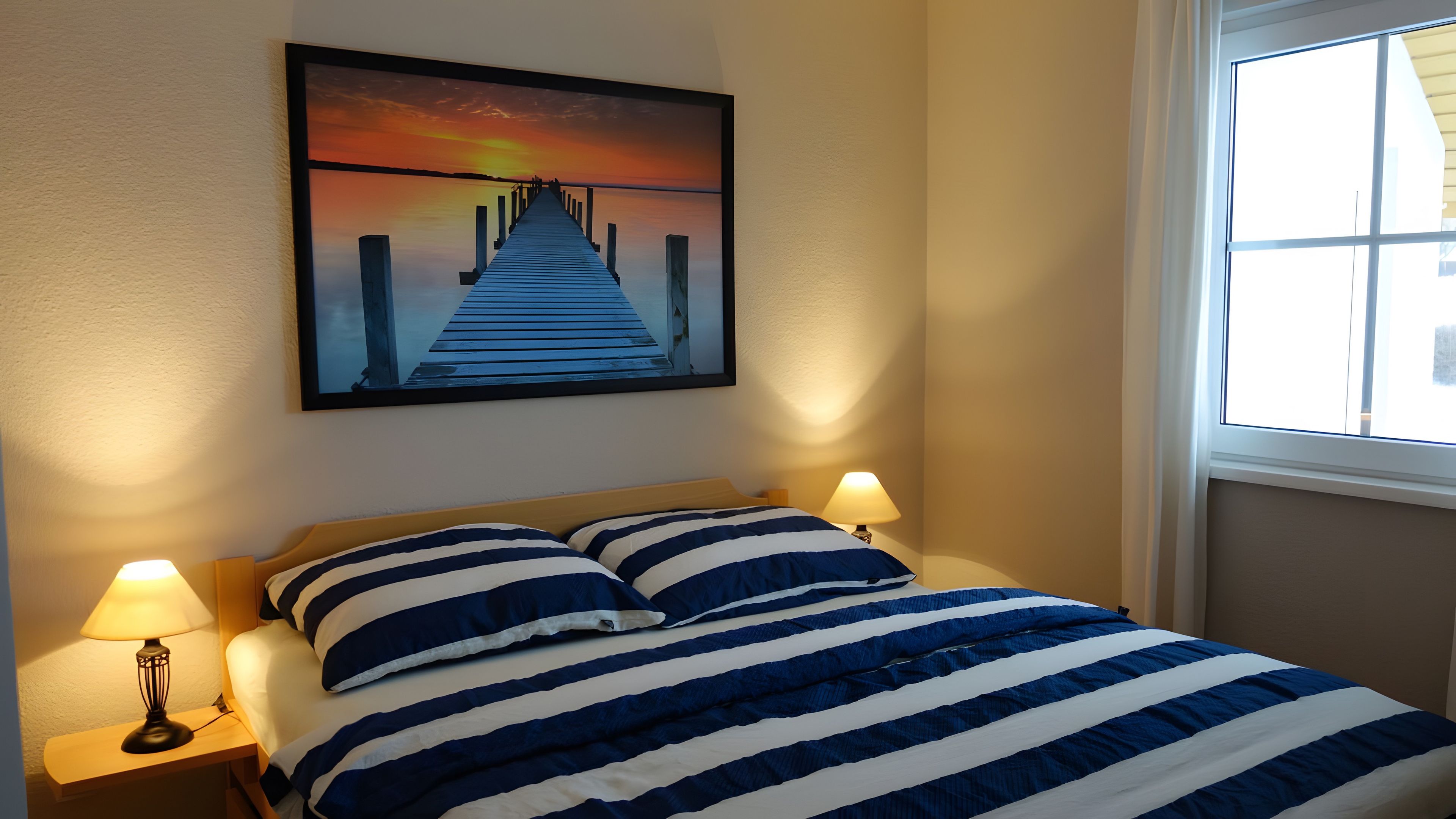 Une chambre à coucher avec un lit, deux lampes de chevet, un tableau accroché au mur et une fenêtre.