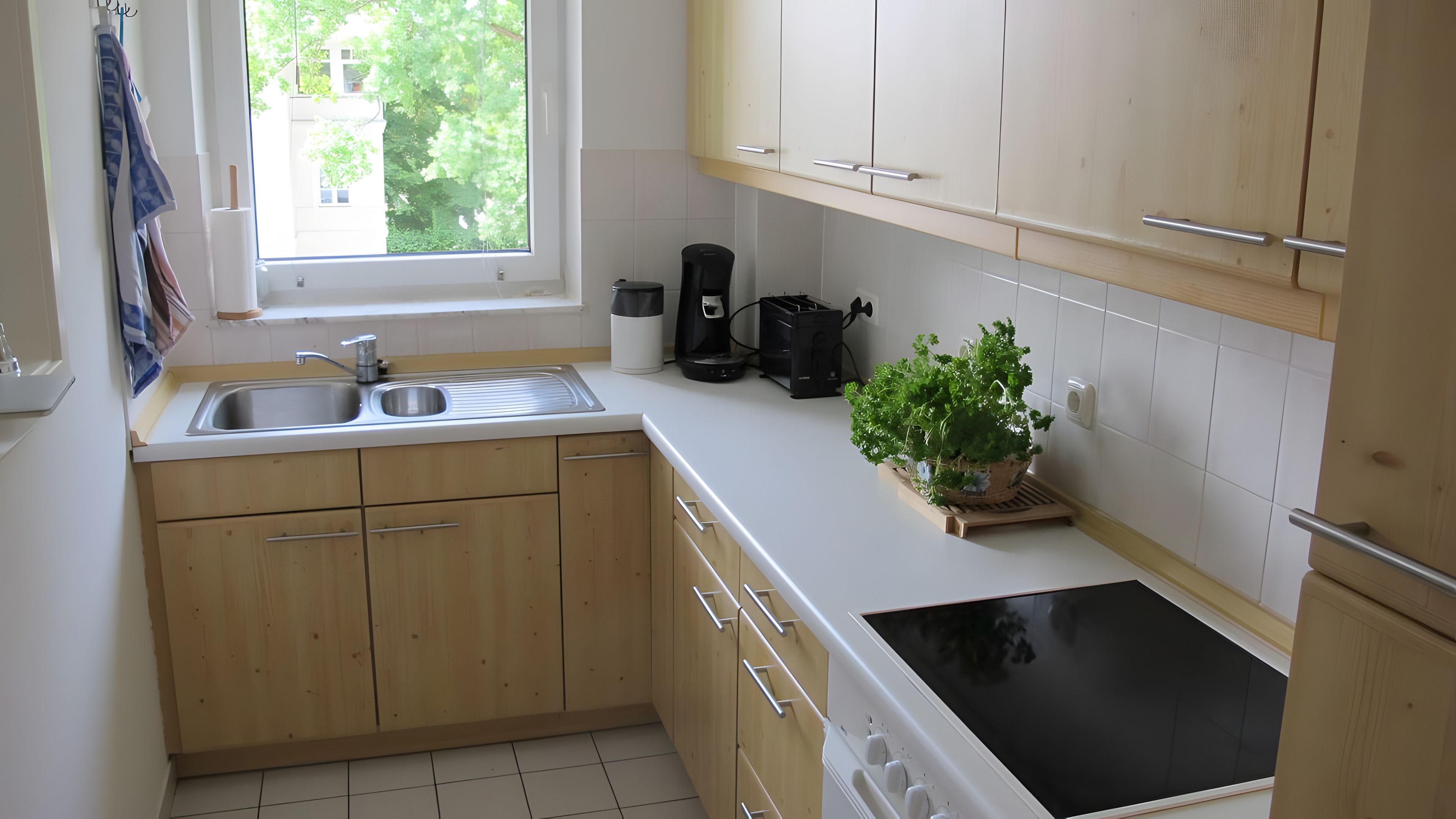 Eine Küche mit Holzausstattung, einer Spüle, einer Kaffeemaschine und einem Blumentopf.