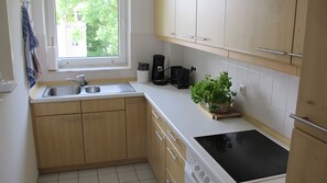 Eine Küche mit Holzausstattung, einer Spüle, einer Kaffeemaschine und einem Blumentopf.