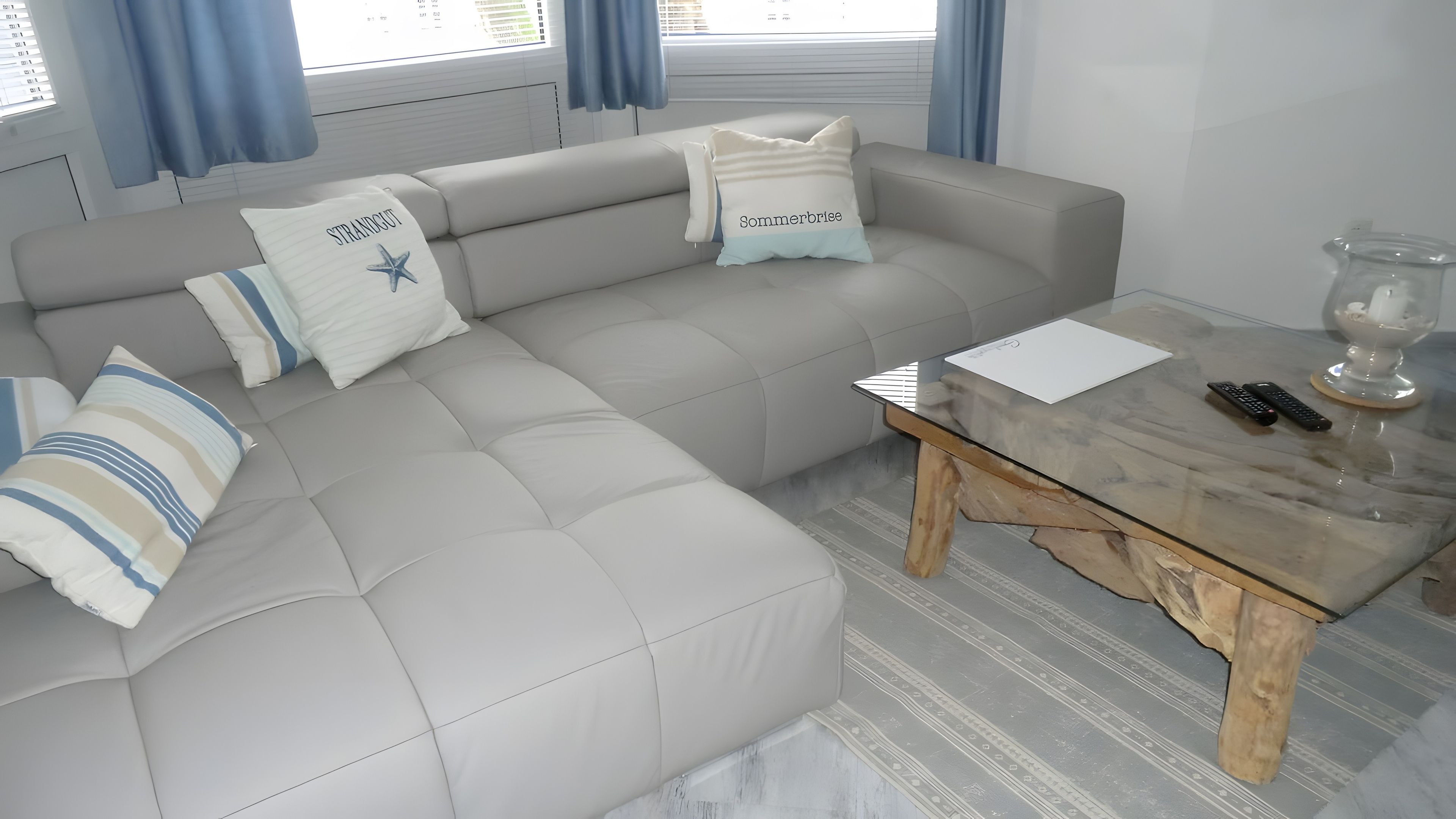Una sala de estar moderna con un sofá gris, almohadones a rayas y una mesa de centro de madera.