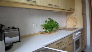 A kitchen with white cabinets, a stainless steel sink, a wooden cutting board, and a built-in oven. - Apartment 'Zinnowitz, Glienbergweg 11A' with Balcony and Wi-Fi (Zinnowitz)