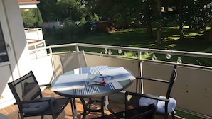 Une table ronde avec des chaises et une vue sur un petit jardin.