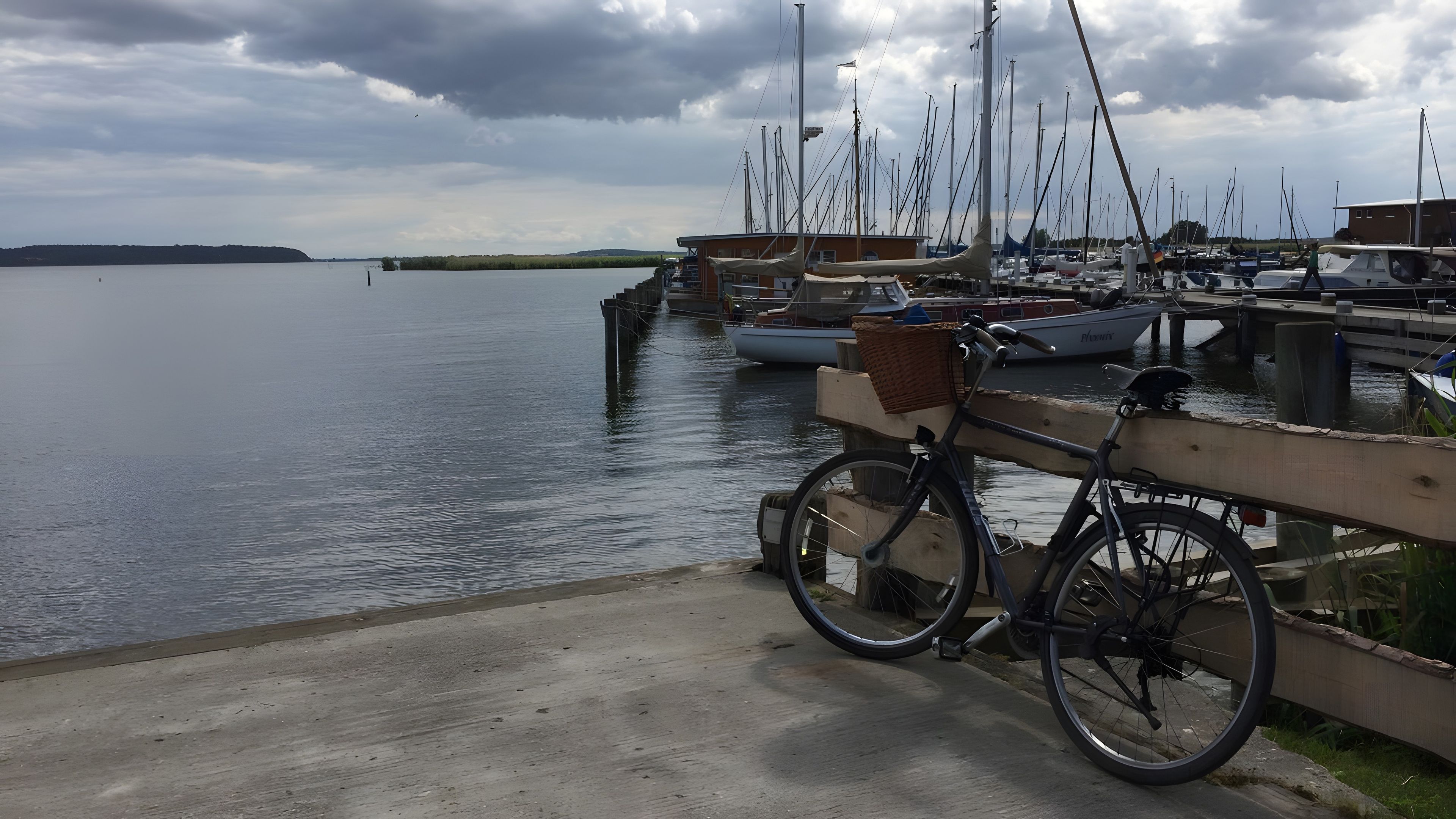 Ein Yachthafen mit vertäuten Booten, einem Fahrrad und einem Holzzaun.