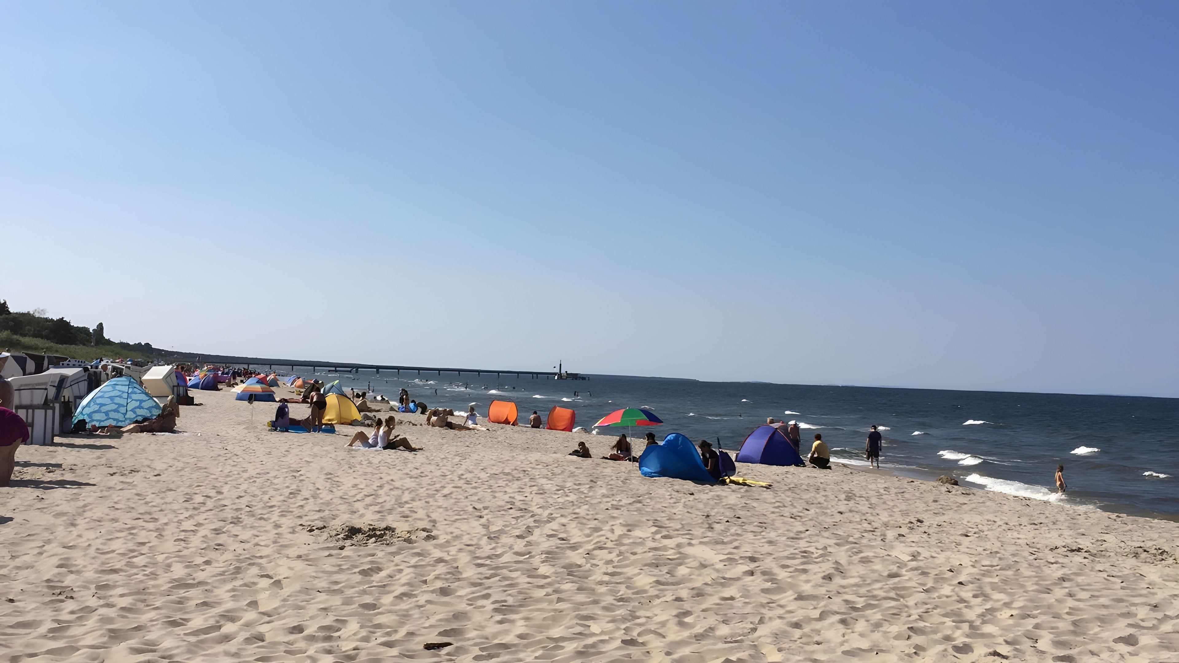 Ein Strand mit Zelten und Menschen.