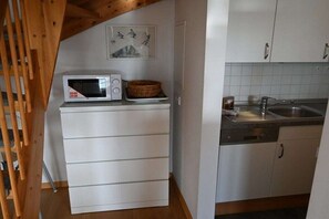 Eine kleine Küche mit einer Mikrowelle, einem weißen Schrank und einem Spülbecken.