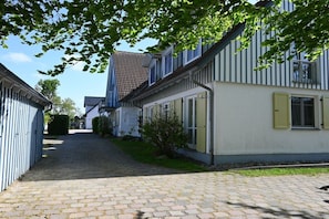 A narrow cobblestone pathway leading to a row of traditional buildings with white facades and blue trim. - Holiday apartment with 2 bedrooms (Prerow)
