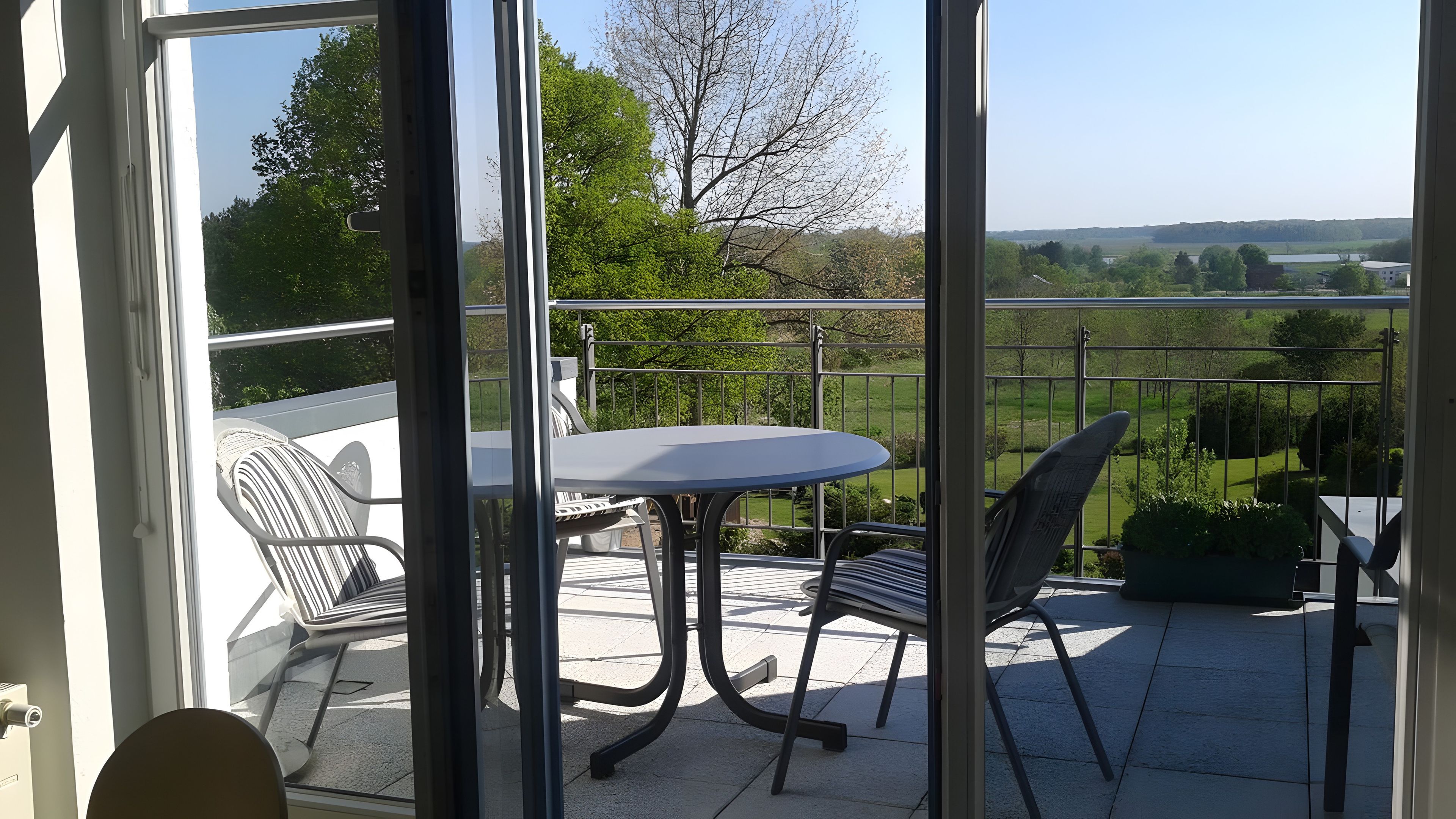 Un balcone con tavolo e sedie, con vista su un paesaggio verde.