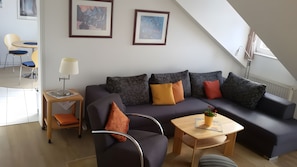 Ein modernes Wohnzimmer mit einer Couch, Sesseln, einem Couchtisch und einer Lampe.