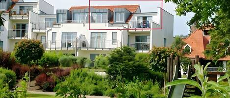 A modern residential building with multiple balconies and a well-maintained garden.