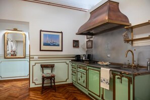 A kitchen with a stove, sink, and a chair. - Regal House Anzio Manetti 16 (Anzio)