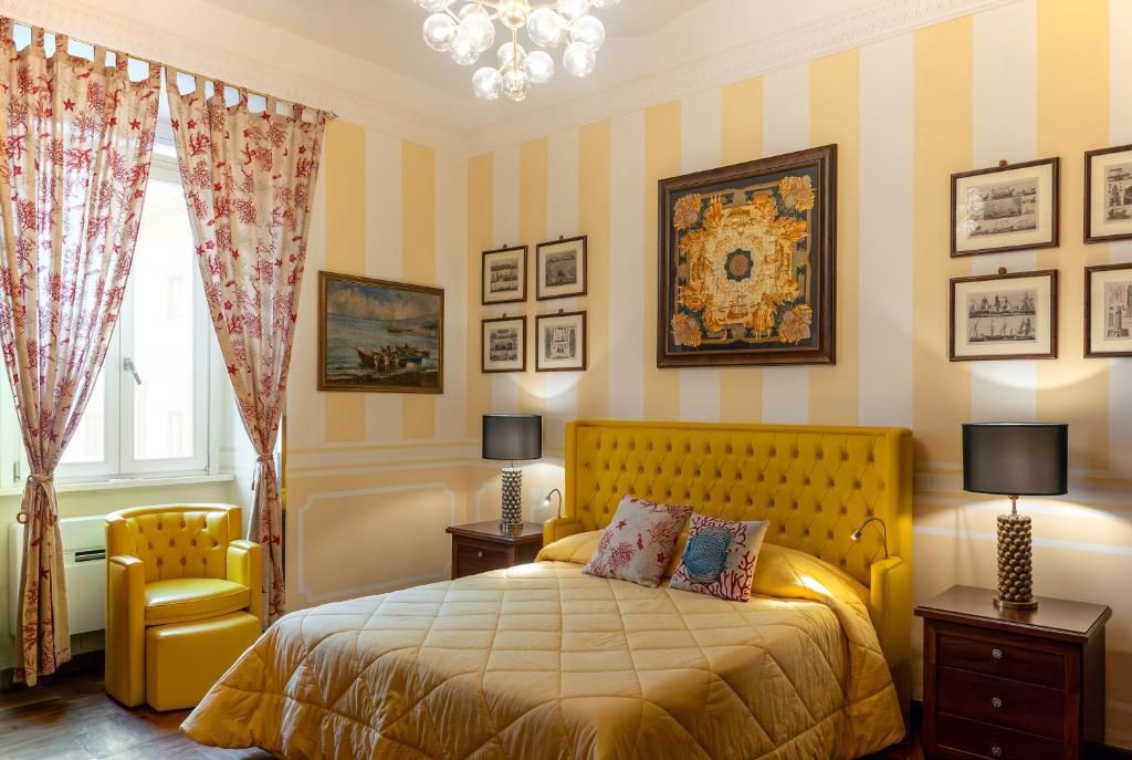 A hotel room with a large bed, a chair, a nightstand, and a wall with framed pictures.