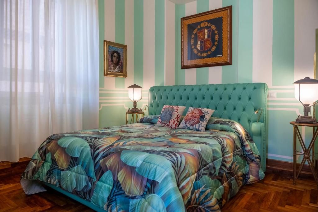 A room with a bed, striped walls, and framed pictures.