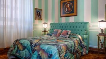 A room with a bed, striped walls, and framed pictures.